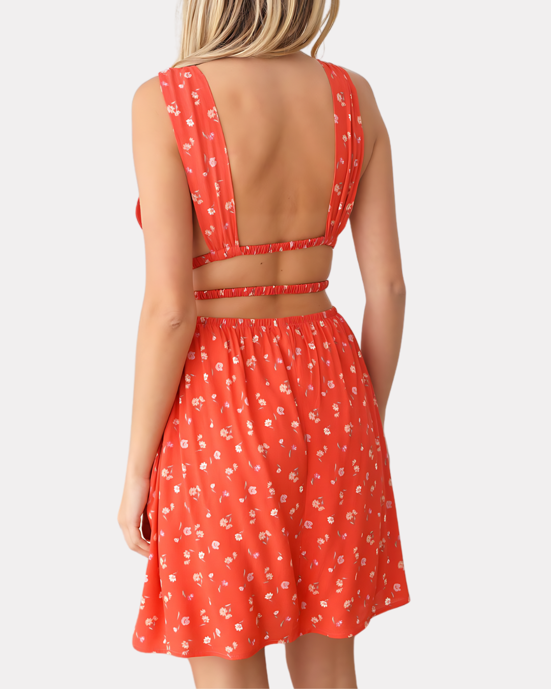 Image of a woman wearing a Floral Delight Mini Dress, featuring a deep V-neck, smocked waist, and an alluring open back with strap detail, perfect for summer.