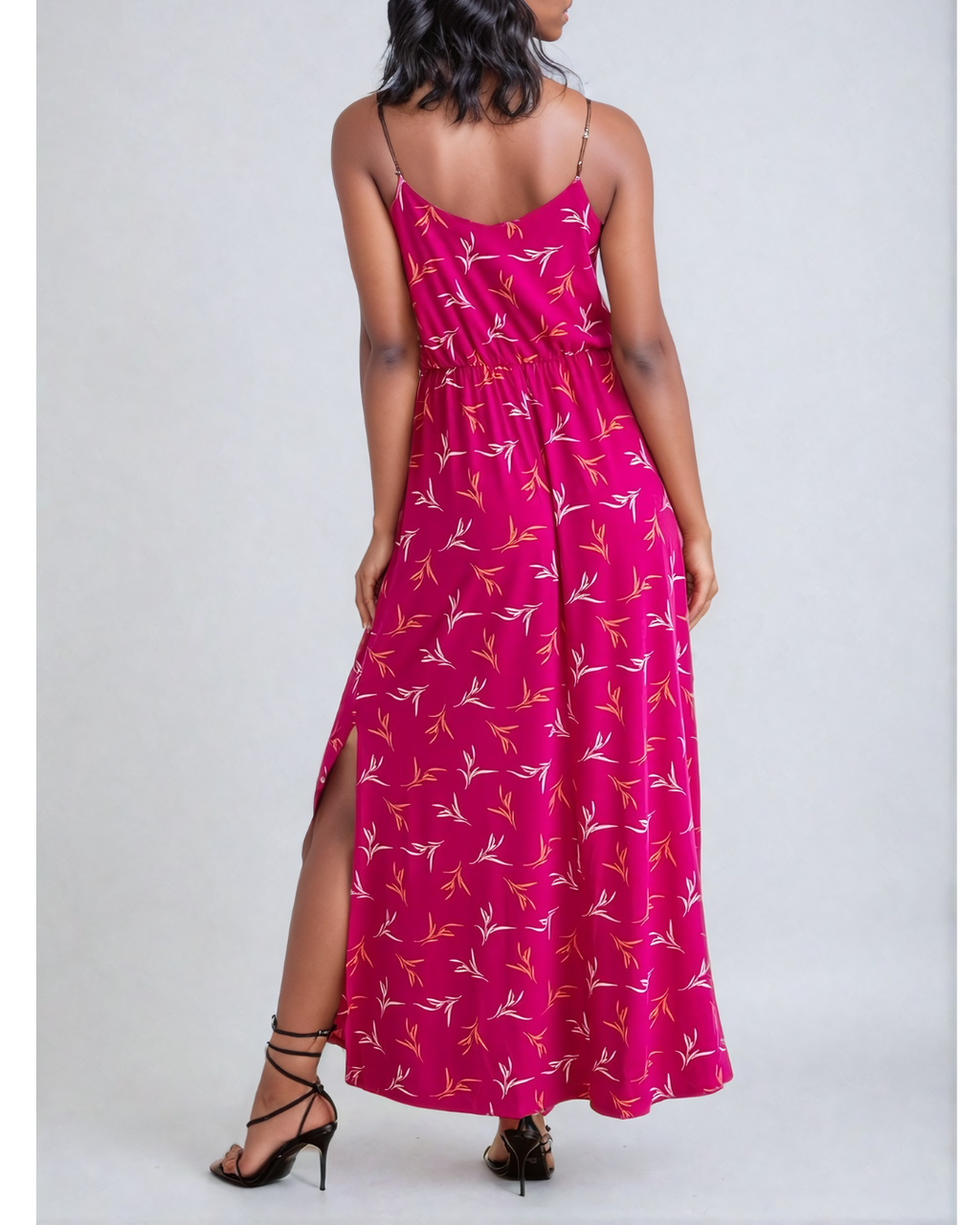 Image of a woman wearing a Fly Away Cami Maxi Dress in a vibrant floral print, suitable for various occasions, with adjustable straps and a flattering cami neckline.