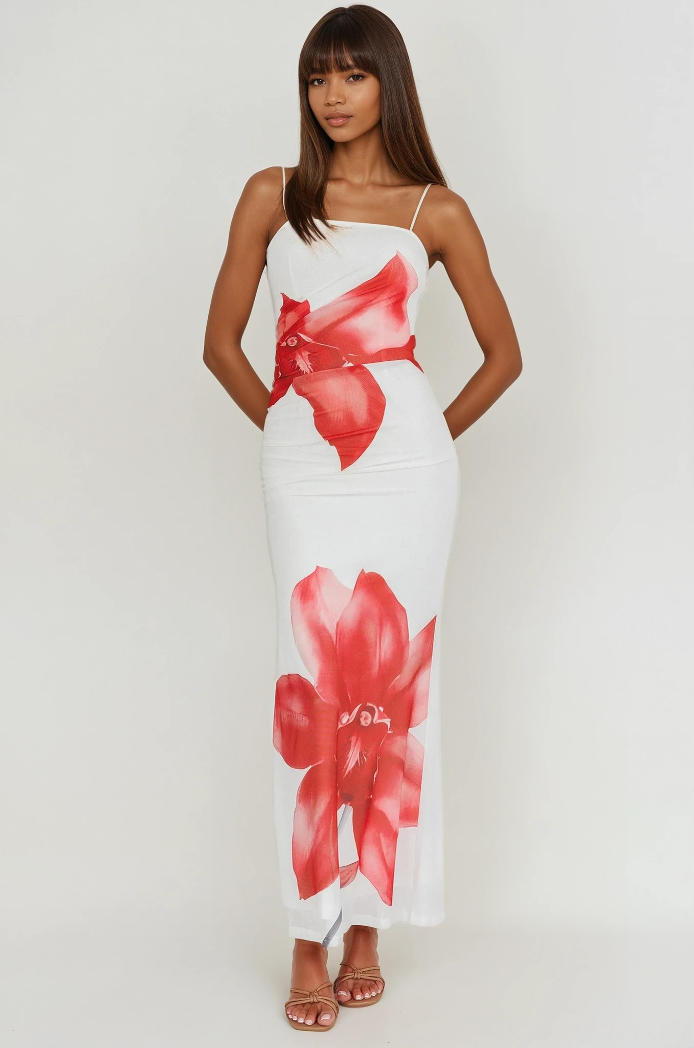 Woman wearing a white dress with red floral patterns on a plain background