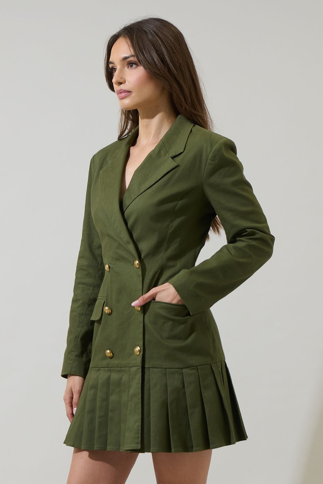 Woman wearing a green blazer dress against a plain background

