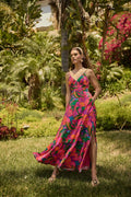 Woman in a colorful dress standing in a garden with lush greenery and flowers.


